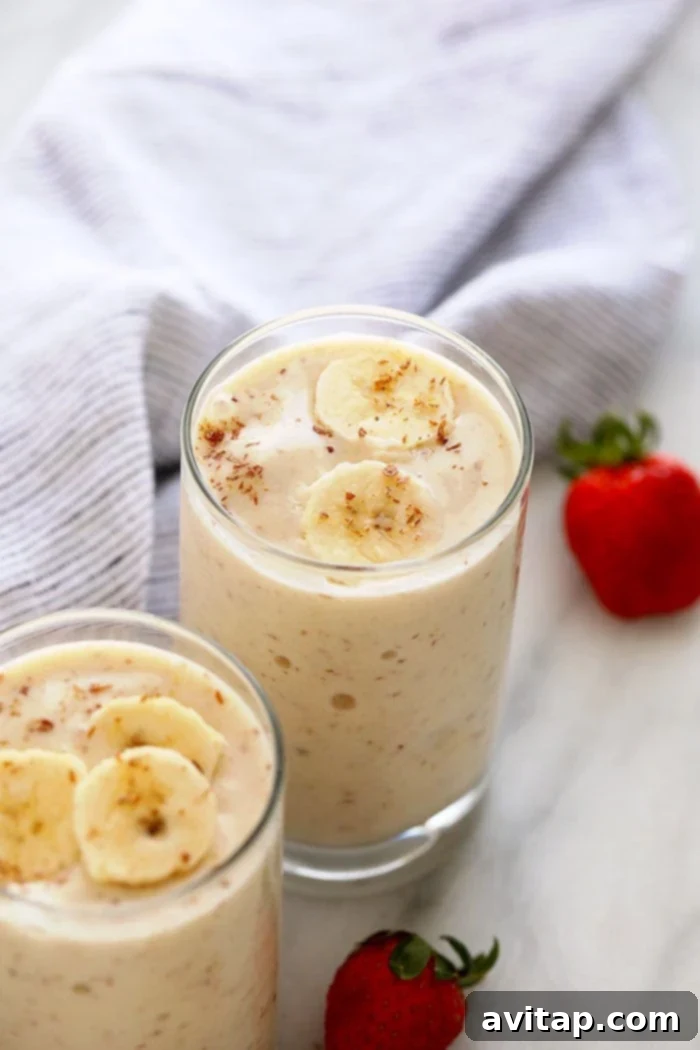 Finish your perfect banana smoothie with an array of delightful toppings. Granola adds a fantastic crunch and texture for a complete meal! A vibrant banana smoothie in a clear glass, topped with granola for added texture and crunch.
