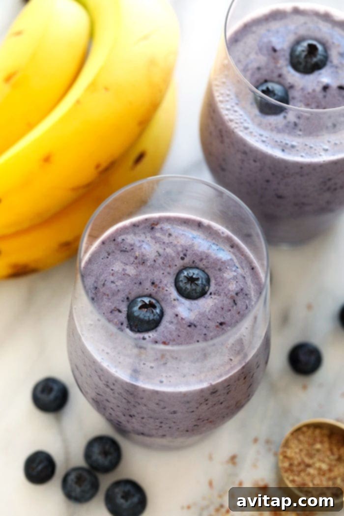 A perfectly thick and vibrant blueberry banana smoothie, ideal for a healthy breakfast or snack. A vibrant blueberry banana smoothie in a clear glass, ready to be enjoyed.