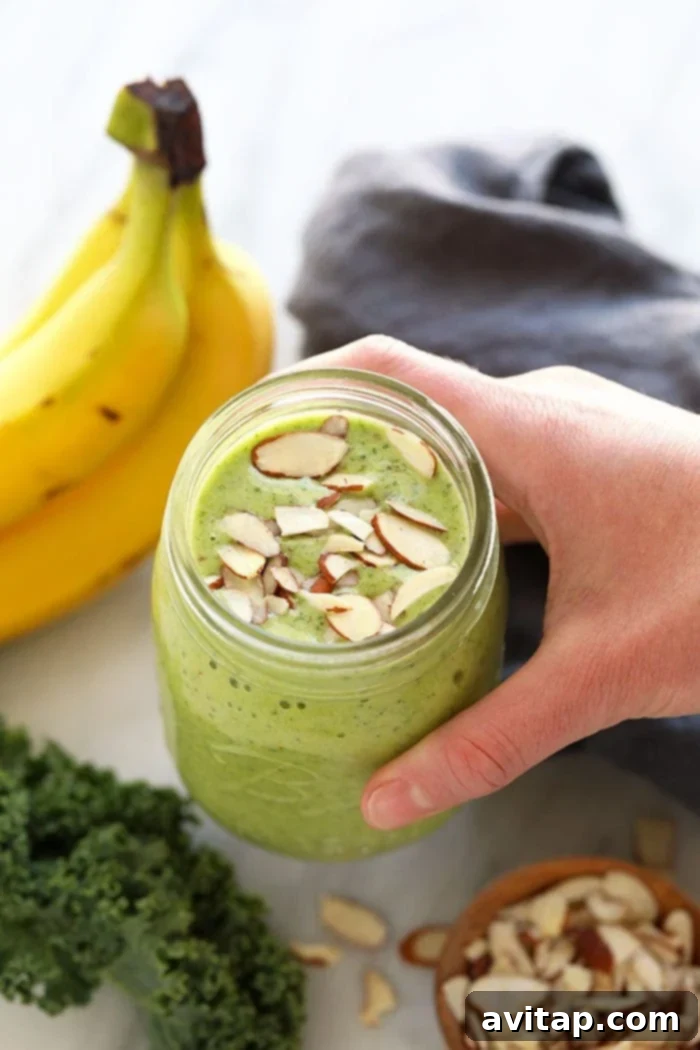 A beautifully topped kale smoothie in a mason jar, garnished with slivered almonds for extra crunch and nutrition.