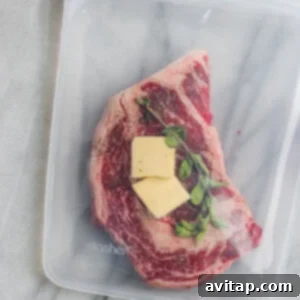 Sous vide steak sealed in a bag with butter and herbs, ready for cooking.