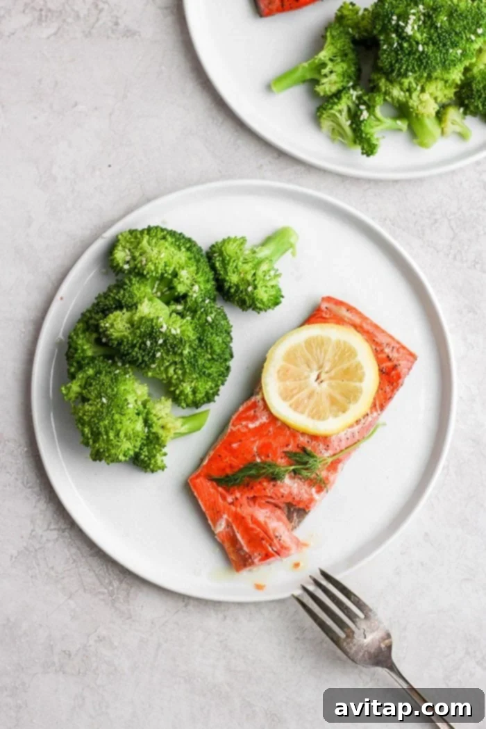 Sous vide salmon on a plate, elegantly plated with a side of fresh broccoli.