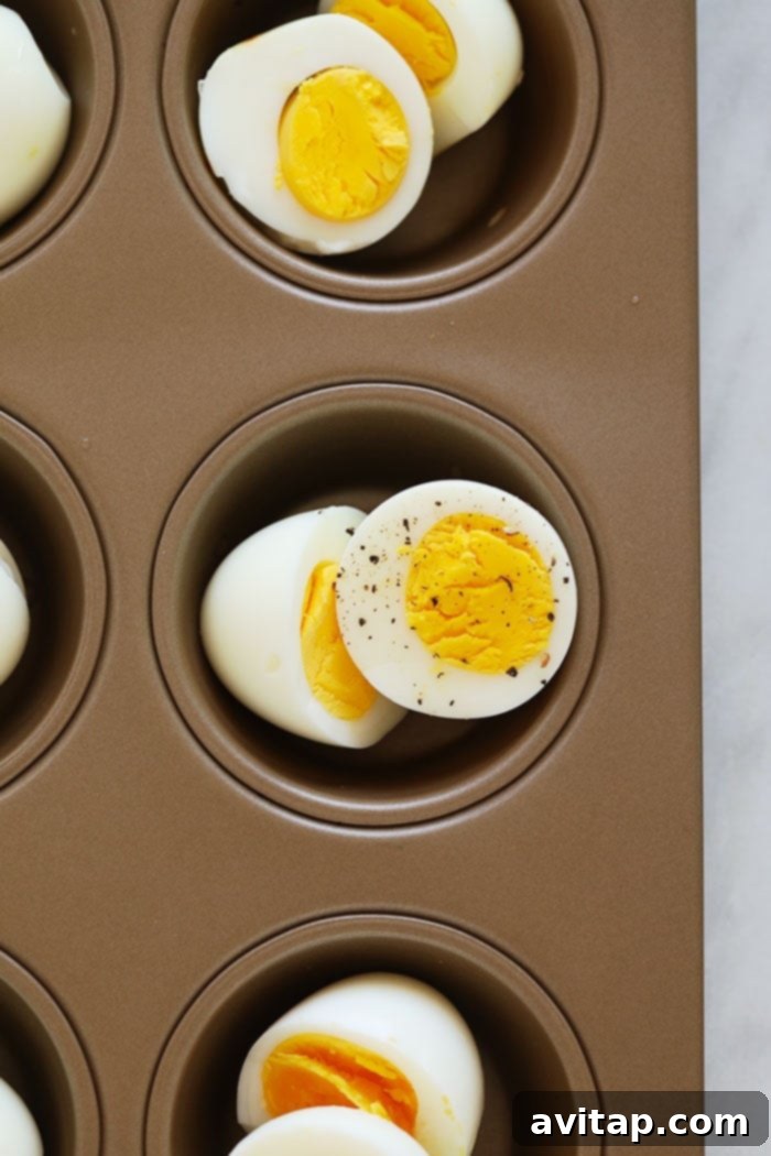 Perfectly baked hard-boiled eggs cooling in a muffin tin after being removed from the oven.