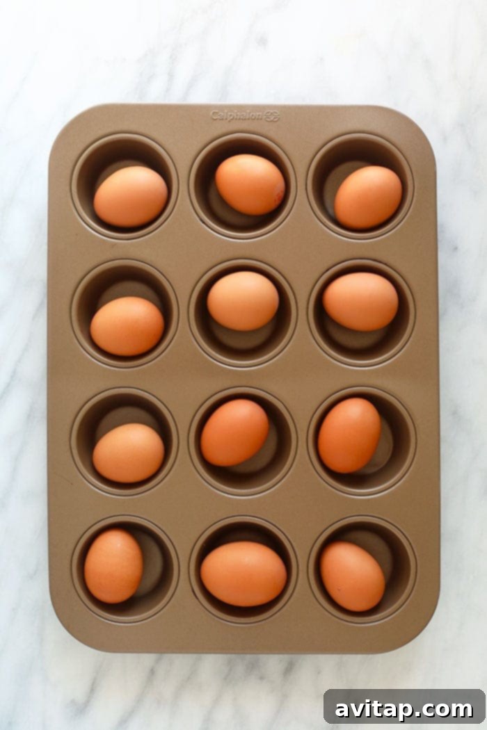 Raw eggs perfectly arranged in a muffin tin, showcasing the simple setup for oven-baked hard-boiled eggs.