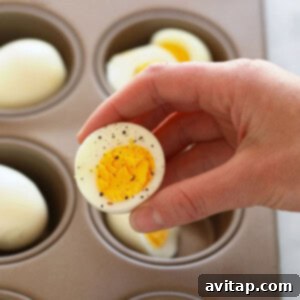 A person using an oven to hard boil eggs in a muffin tin.
