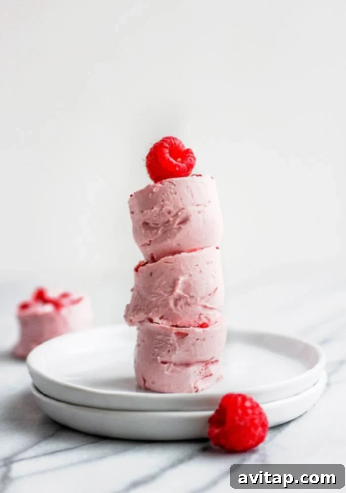 Stacked raspberry cheesecake fat bombs with fresh raspberries on top