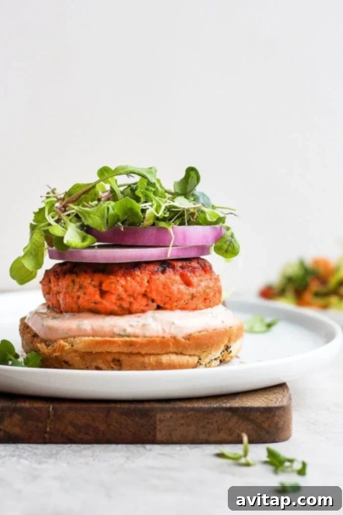 Delicious lemon dill salmon burgers with sriracha aioli, served on a bun with fresh toppings.