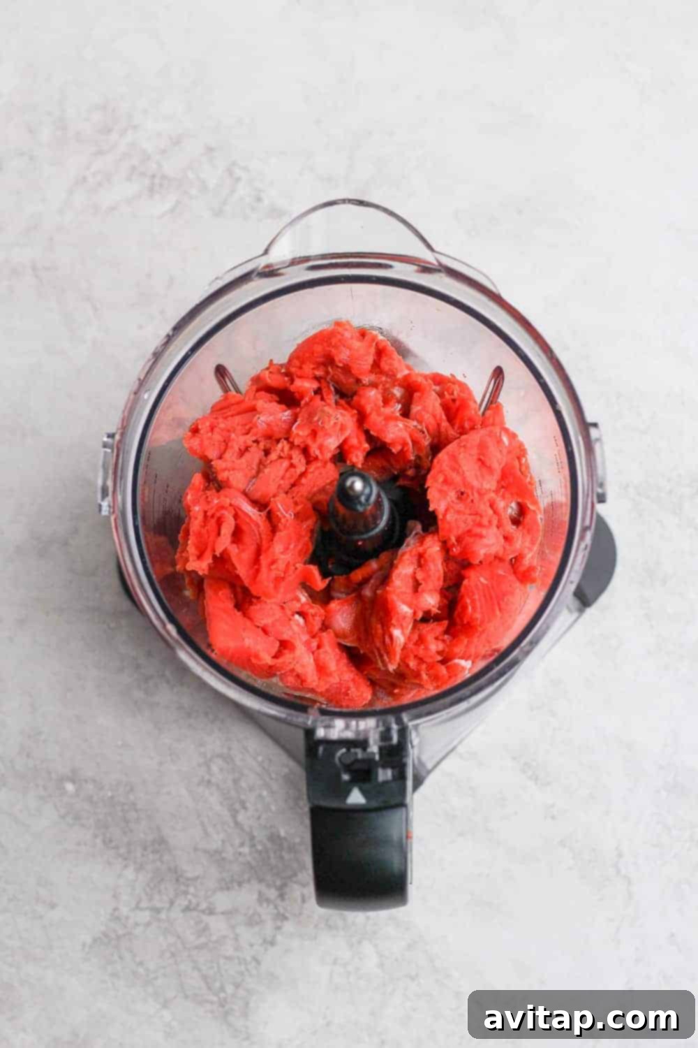 Chunks of fresh salmon being prepped in a food processor for homemade salmon burgers.