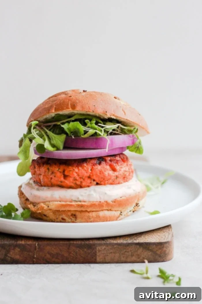 Cooked lemon dill salmon burgers on a plate, ready to be served with fresh toppings.