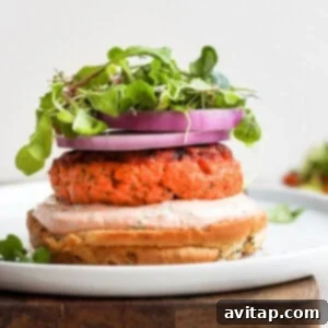 Delicious salmon burgers served with arugula and red onion on a white plate.