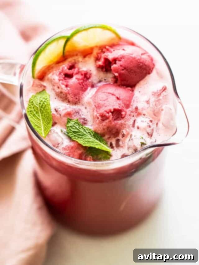 A glass of refreshing Summer Punch with fruit slices and mint.
