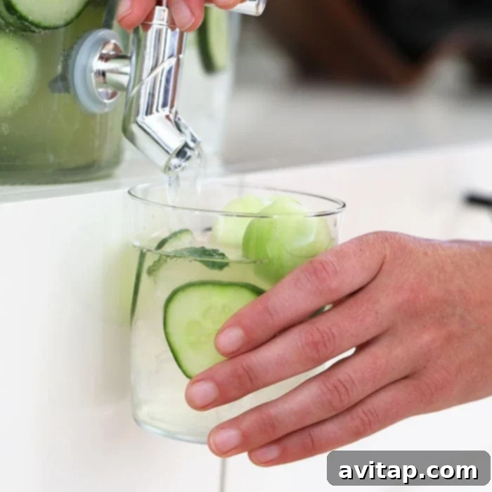 Cucumber Melon Ginger Punch in a pitcher with sliced cucumber and melon