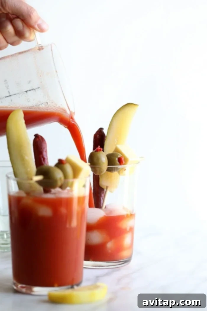 Pouring Bloody Mary Mix into a glass, highlighting the rich red color and fresh ingredients