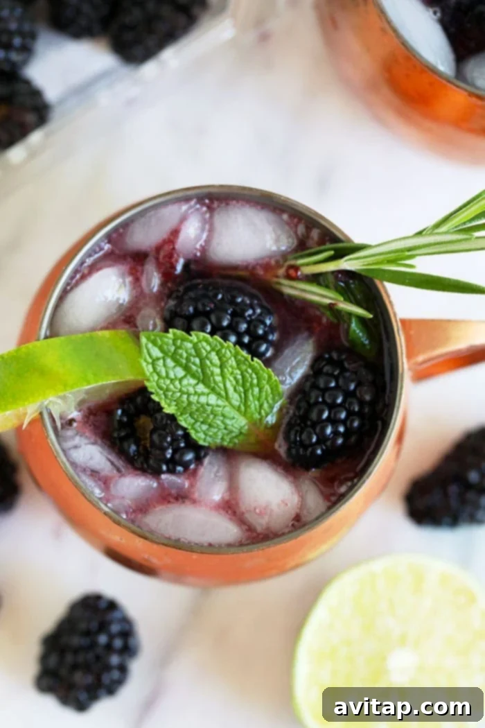 Close-up of a Blackberry Moscow Mule with fresh blackberries, mint, and a rosemary sprig garnish