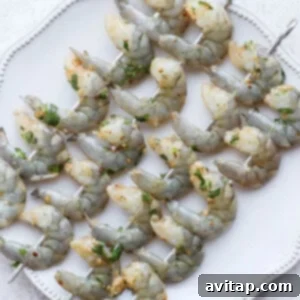 Raw shrimp threaded onto skewers, ready for grilling.