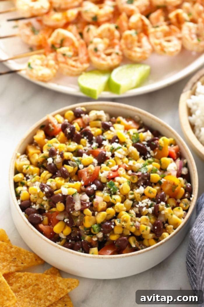 Vibrant black bean and corn salad alongside grilled shrimp skewers.