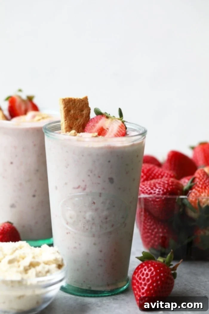Creamy Strawberry Protein Shake 4 A tall glass of strawberry cheesecake protein smoothie, garnished with fresh strawberries.