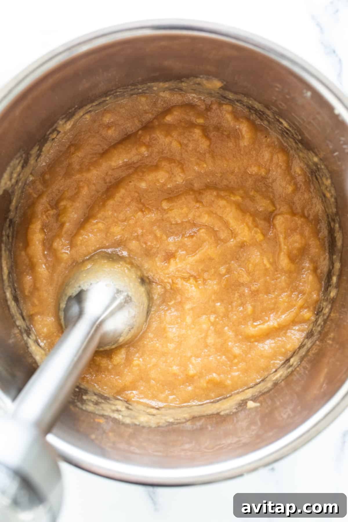 Smooth, homemade applesauce in a serving bowl with a spoon.