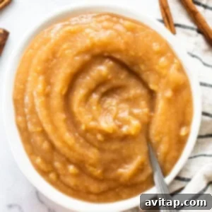 Apple butter in a white bowl with cinnamon sticks.