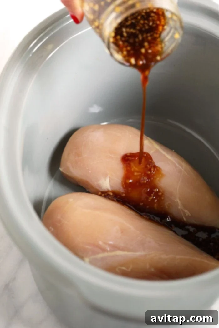Homemade Teriyaki Sauce: The Key to Flavorful Chicken Rich teriyaki sauce being poured over raw chicken breasts, ready for slow cooking.
