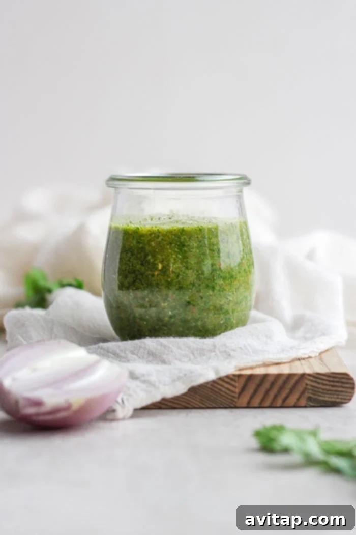 Close-up of vibrant chimichurri sauce in a glass jar, showcasing its fresh herb texture