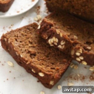 A slice of pumpkin bread with cinnamon and oats on a white plate.