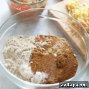 The combined dry ingredients for apple cinnamon pancakes in a bowl, next to a measuring cup and loaf of bread.