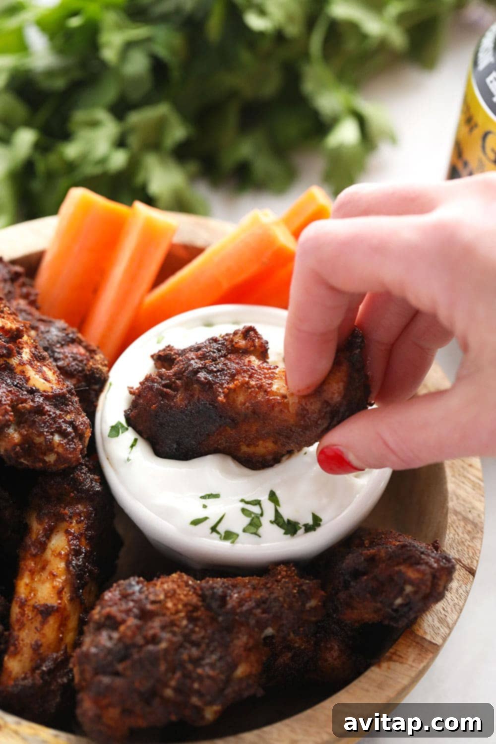 Dipping Crispy Chicken Wing Close-up of a perfectly baked dry rub chicken wing being dipped into a bowl of creamy blue cheese dressing.