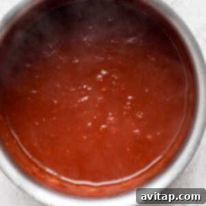 Homemade BBQ sauce simmering in a saucepan on low heat.