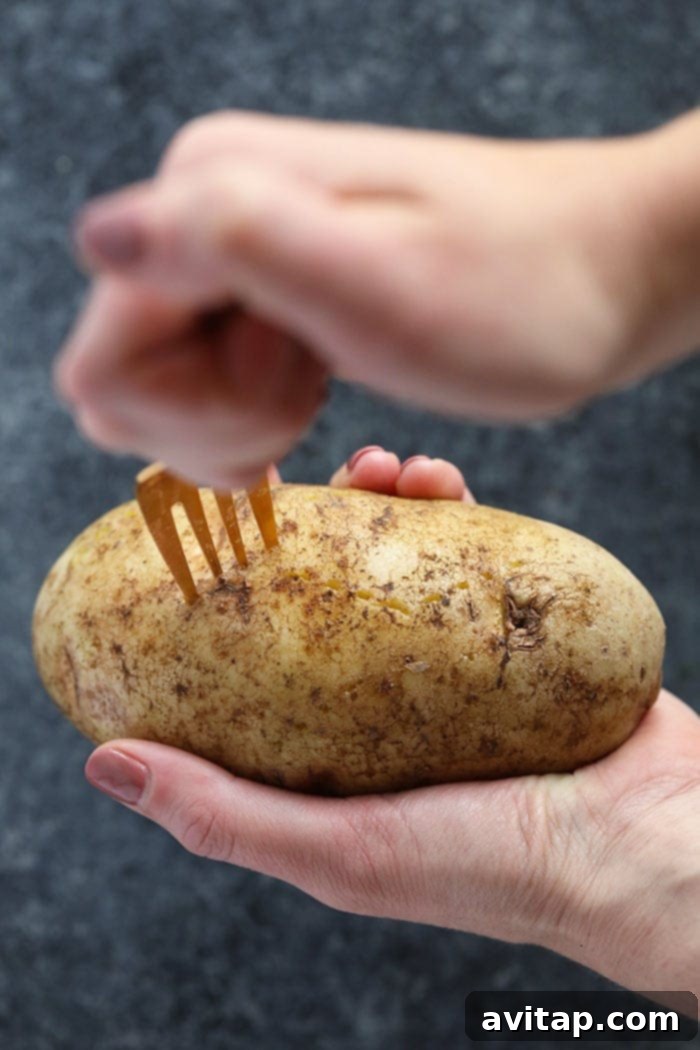 A fork piercing a crock pot baked potato, showing its fluffy interior and tender skin.