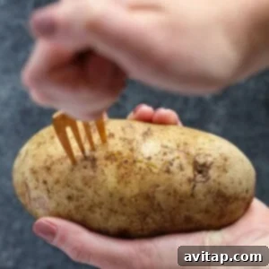 A person holding a potato with a fork, preparing crock pot baked potatoes.