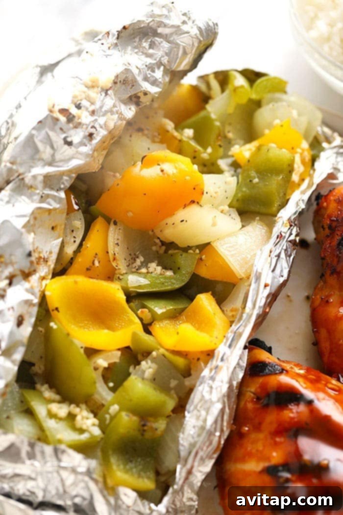 Colorful grilled peppers and onions nestled in a foil pack, ready for the grill