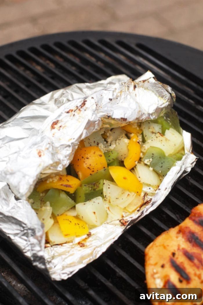 Foil pack with grilled peppers and onions cooling on the barbecue grate