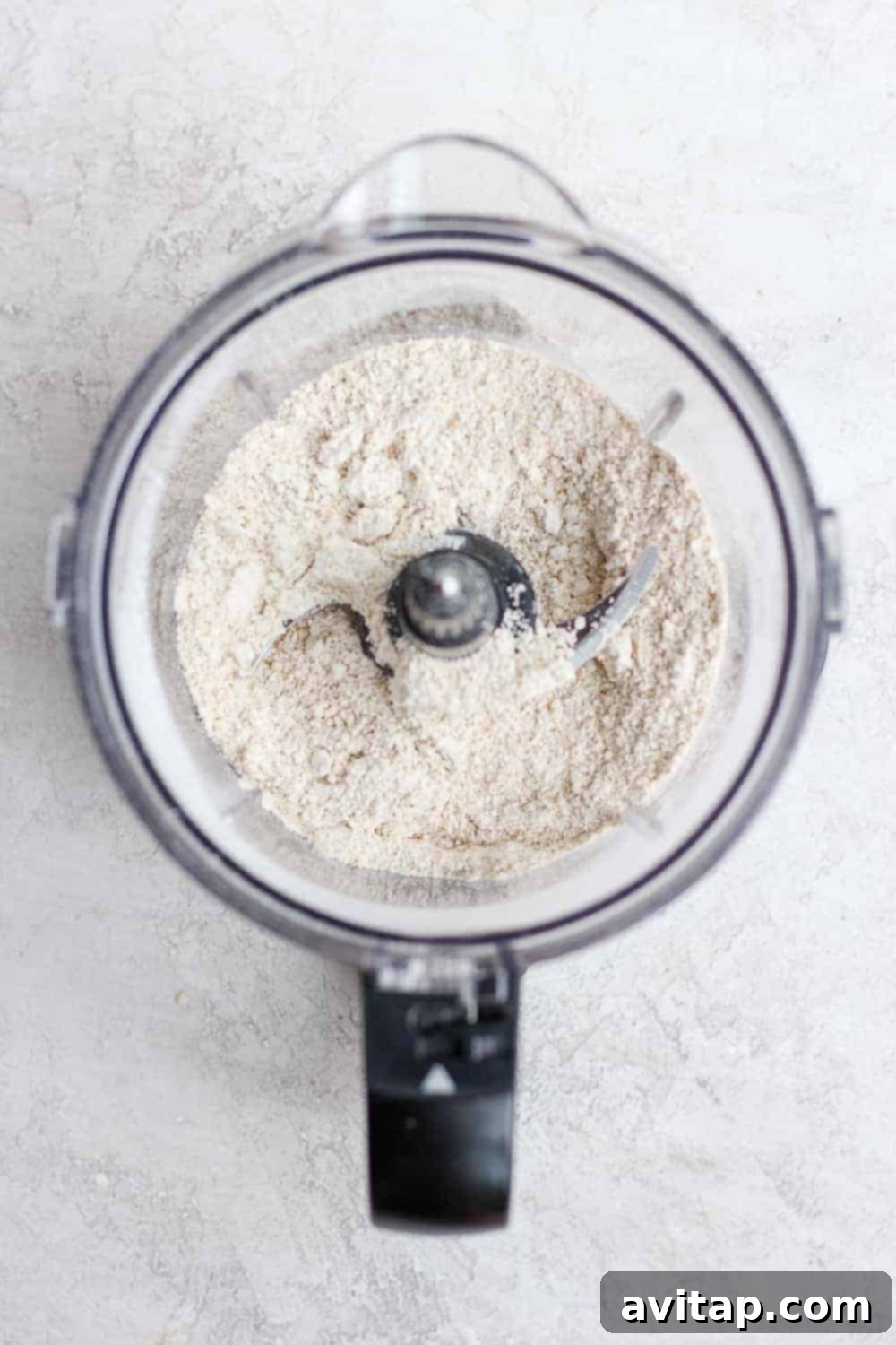 Close-up of rolled oats being processed into fine oat flour in a food processor.