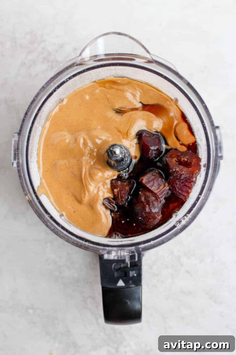 Various ingredients for cookie dough bites, including dates, oats, and cashew butter, ready in a food processor.