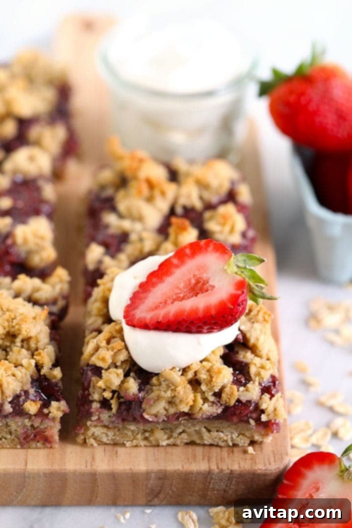 strawberry oatmeal bars sliced on a cutting board and topped with a strawberry