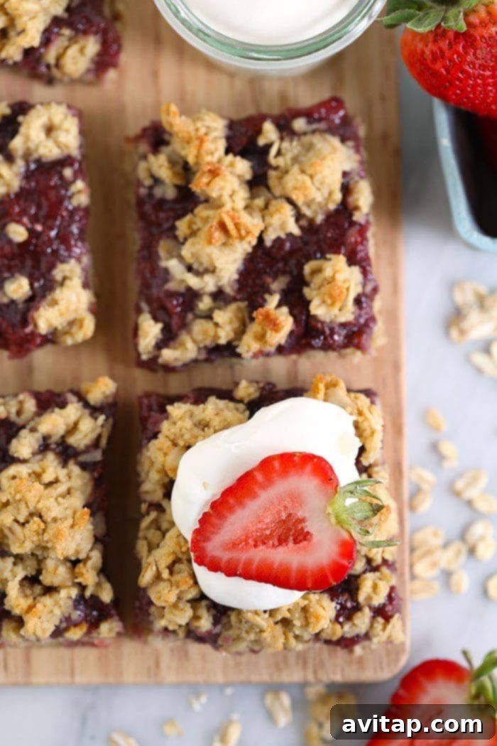 sliced strawberry oatmeal bars topped with whipped cream and a fresh strawberry