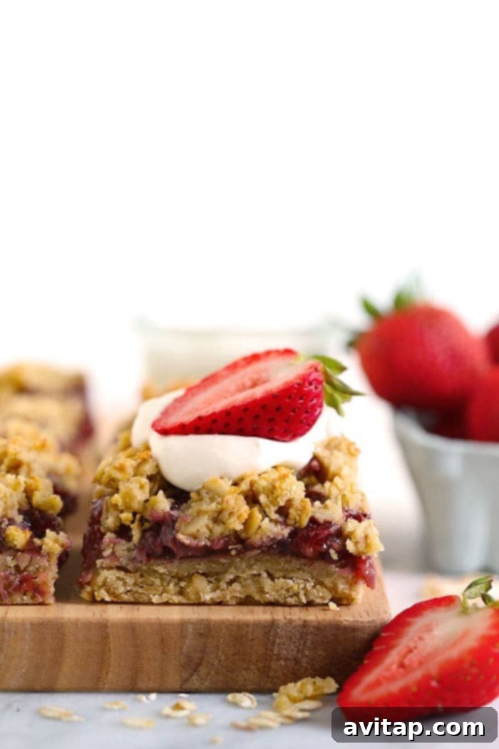 strawberry oatmeal bar sliced and topped with whipped cream and a sliced fresh strawberry