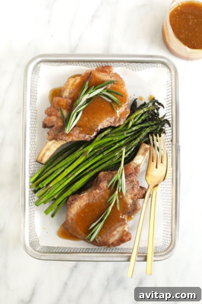 Two Instant Pot pork chops, drizzled with rich whiskey gravy, served with fresh green asparagus.