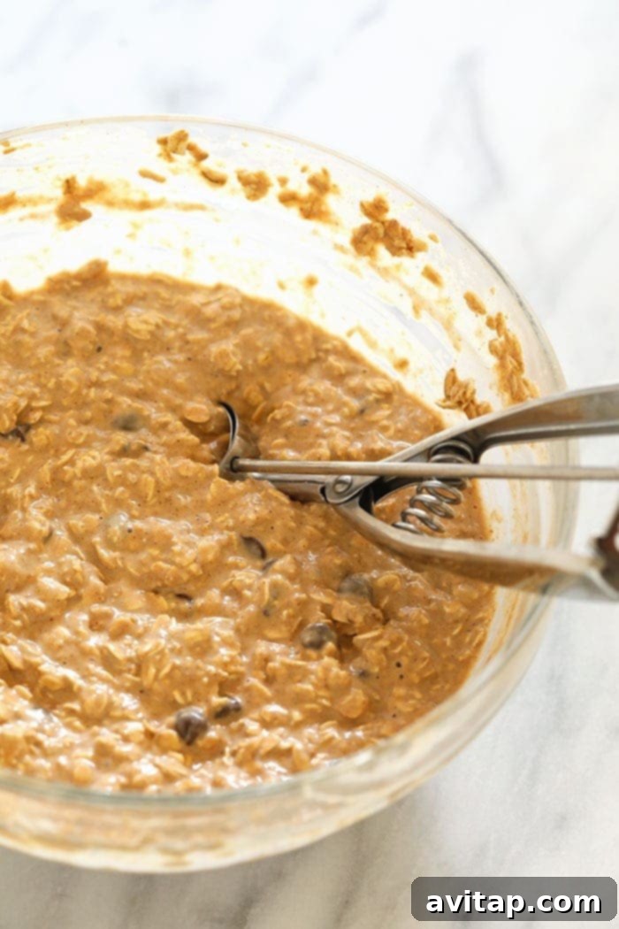 A bowl of mixed peanut butter chocolate chip oatmeal batter, ready to be scooped into muffin tins.