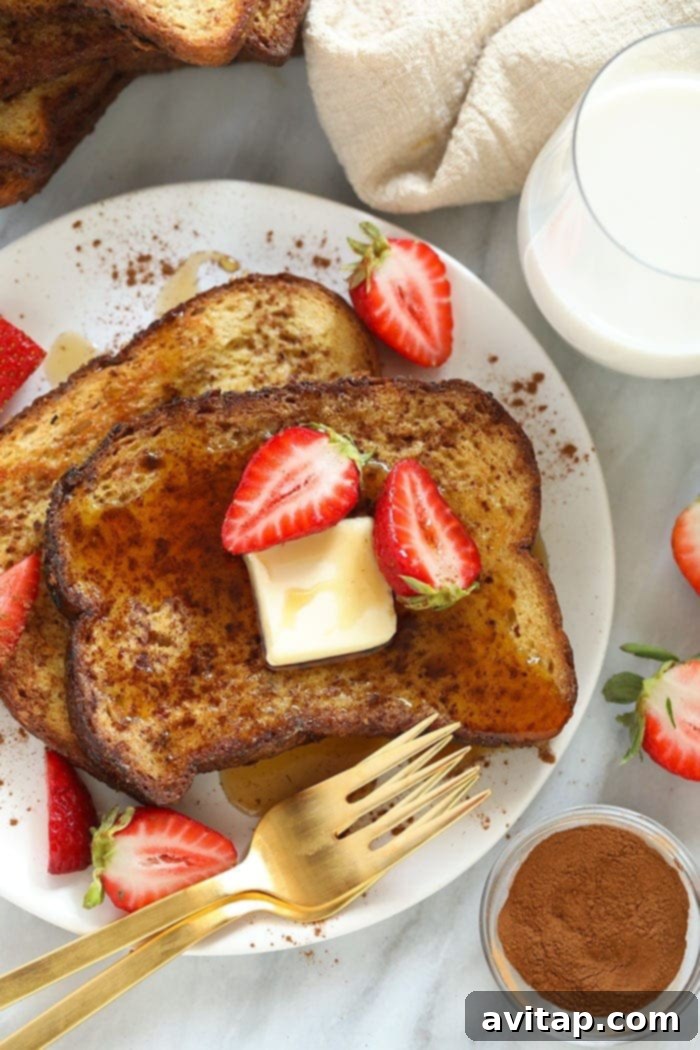 Sheet pan French toast beautifully arranged on a white plate, garnished with fresh strawberries and a delicate drizzle of maple syrup, ready to be enjoyed as a delightful brunch.