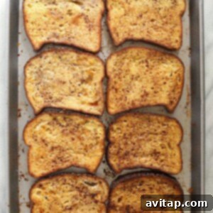 Effortless Baked French Toast 10 Four slices of french toast on a sheet pan.