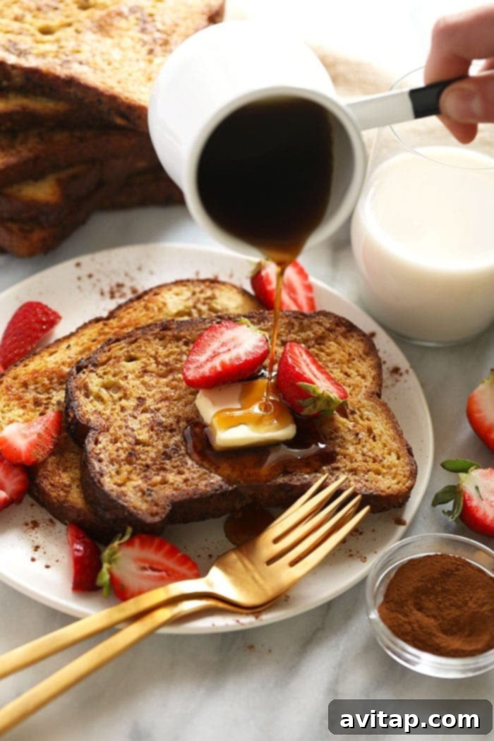 Effortless Baked French Toast 7 A plate of golden-brown sheet pan French toast generously drizzled with rich maple syrup, ready to be enjoyed.