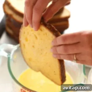 Effortless Baked French Toast 9 A person placing a slice of bread onto a sheet pan for French toast.