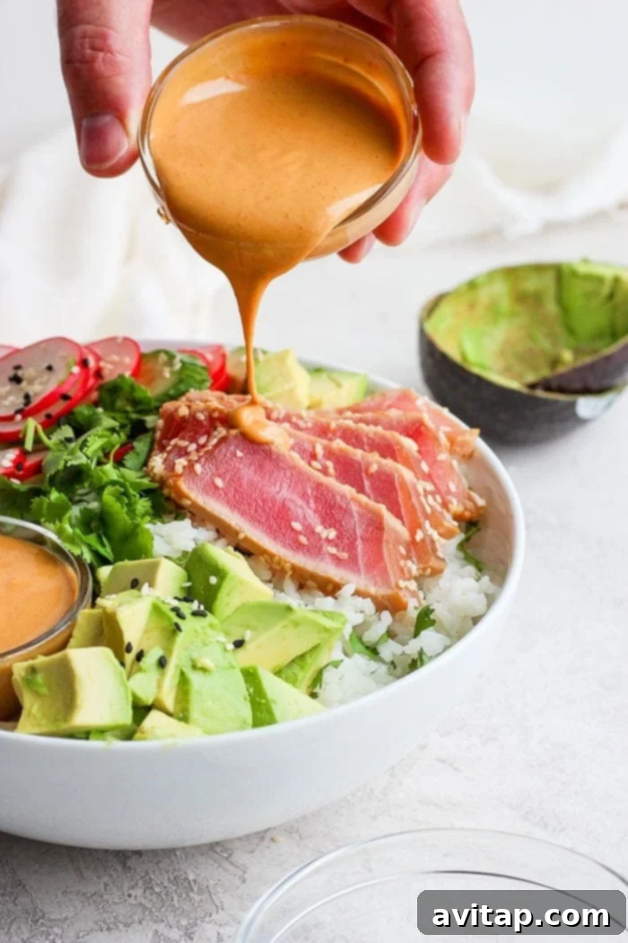 Drizzling almond dressing onto the poke bowl