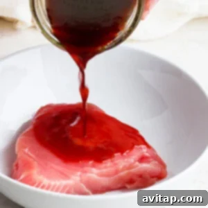 A person is pouring a sauce on an ahi poke bowl.