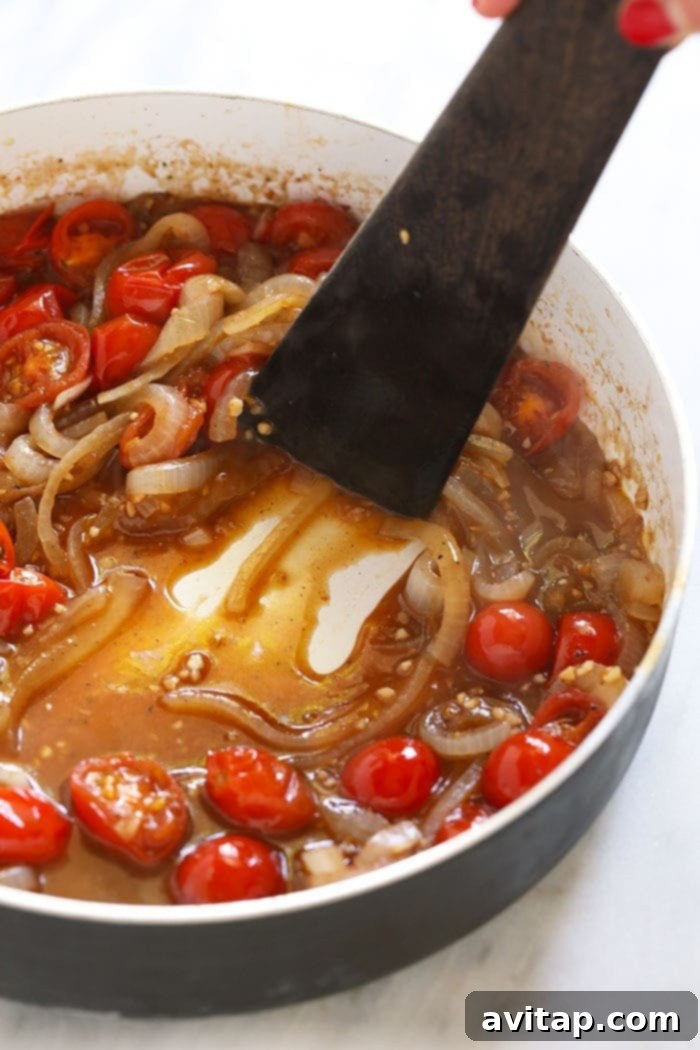 Preparing the delicious white wine balsamic reduction sauce for BLT pasta. Rich and creamy BLT pasta sauce simmering in a skillet with cherry tomatoes and sautéed onions