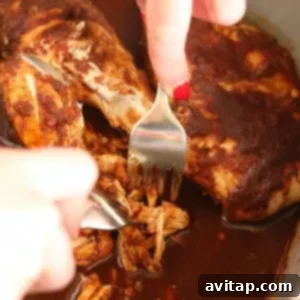 A person prepares slow cooker pulled chicken by pouring sauce over it.