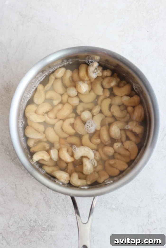 Raw cashews soaking in a saucepan, an essential step for the creamy cashew sauce.