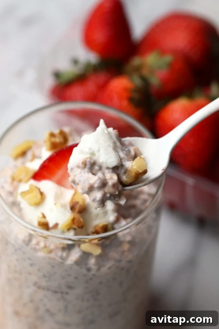 A spoonful of creamy vanilla strawberry overnight oats topped with walnuts and a fresh strawberry