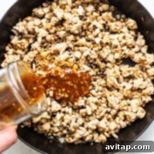 Thickened hoisin sauce coating the chicken and vegetable filling in a skillet, creating a glossy finish.